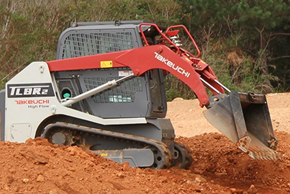 Takeuchi TL8R2 track loader moving dirt on jobsite with bucket attachment.