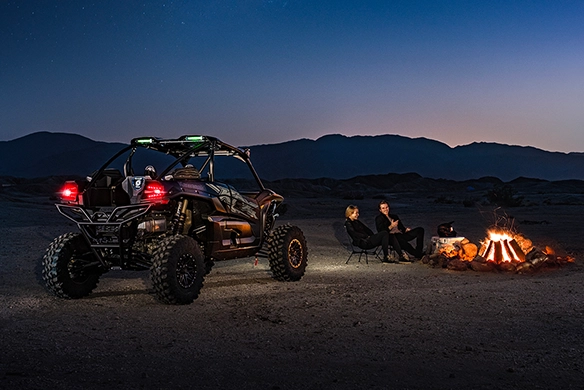 Kawasaki Teryx KRX 1000 Black Out Edition parked near a campfire at night in the desert