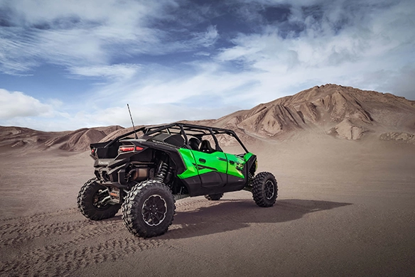 Rear view of Kawasaki Teryx 4 H2 off-road vehicle with green body in sandy landscape