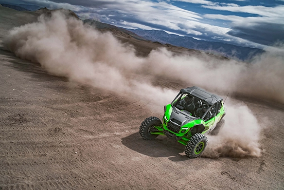 Kawasaki Teryx 4 H2 making a wide high-speed turn in desert sand with dust trail
