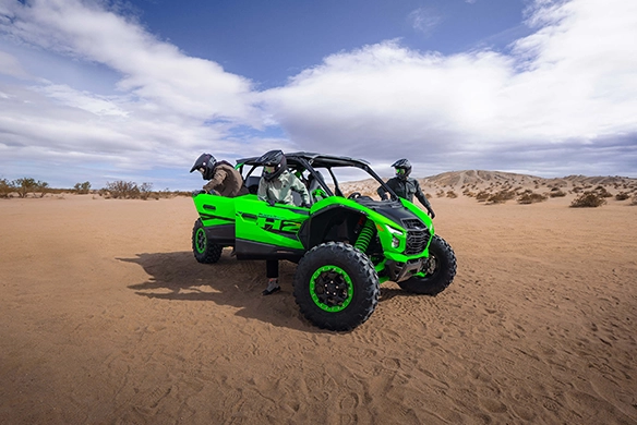 Kawasaki Teryx 5 H2 parked in sandy terrain with riders preparing for off-road adventure