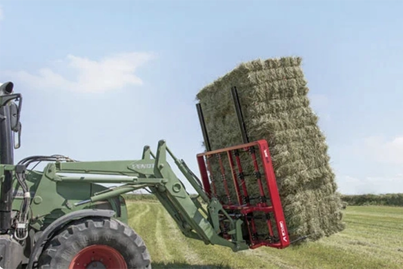 Tractor front loader equipped with an Arcusin bale handler carrying a tall stack of green hay bales.