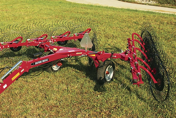 Bush Hog wheel rake on a grassy field with curved tines extended