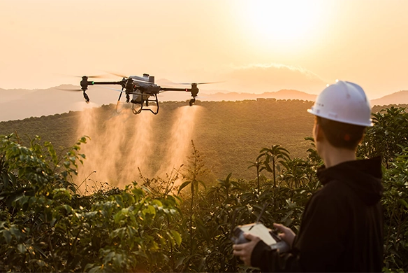 Farmer operating a DJI agriculture drone spraying crops at sunset over a Texas hillside farm