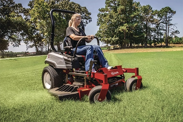 Exmark RADIUS zero-turn mower shown from a low angle, positioned in front of a suburban home.