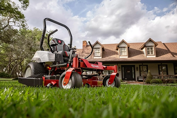 Woman mowing a wide green lawn with an Exmark RADIUS mower in a spacious outdoor area.
