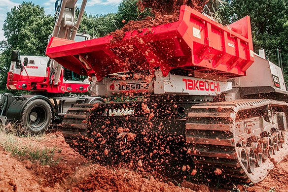 Takeuchi TCR50 crawler dumper in action, unloading dirt on a construction site in Texas, with Takeuchi TB235W excavator in the background