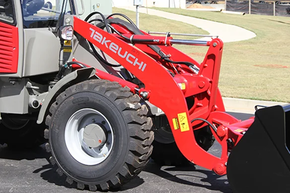 Takeuchi compact wheel loader with front-end bucket attachment parked on pavement at a job site in Texas
