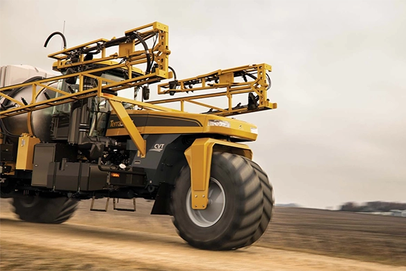 TerraGator liquid applicator driving on a farm road with boom arms folded
