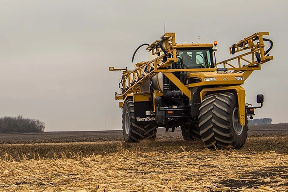 TerraGator liquid applicator working in a stubble field with boom arms open