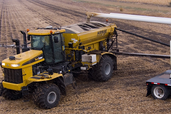 TerraGator AirMax dry spreader applying fertilizer in a field next to a tender truck.
