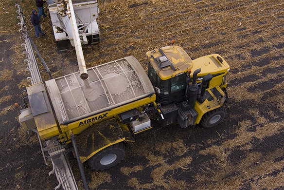 Aerial view of a TerraGator AirMax dry spreader being loaded with fertilizer from a tender truck.