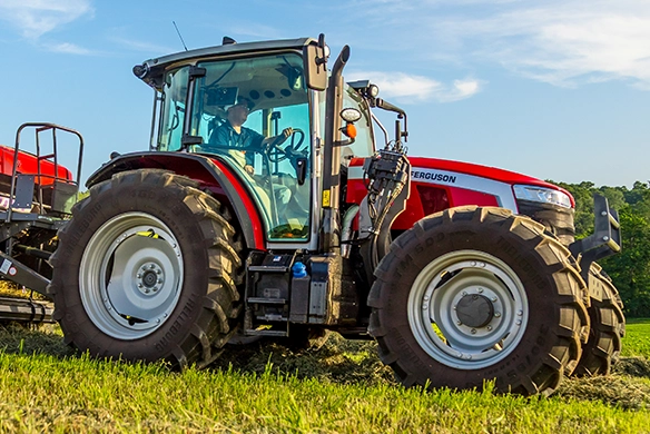 Massey Ferguson 5M Series mid-range tractor in side profile working in a green hayfield.
