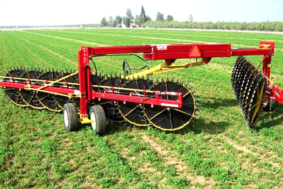 DARF hay rake with multiple wheel rakes in use on a green alfalfa field, designed for efficient windrowing.
