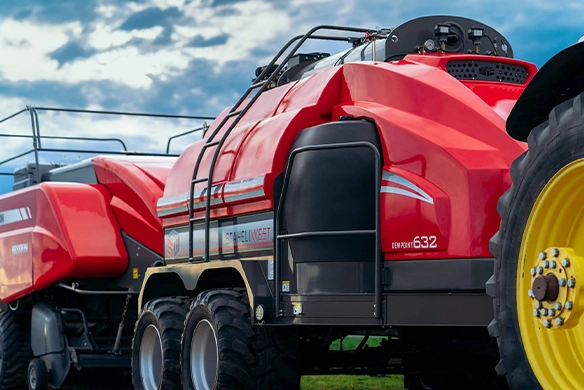 John Deere tractor towing Staheli West DewPoint 632 steamer through a hayfield with steam visible.