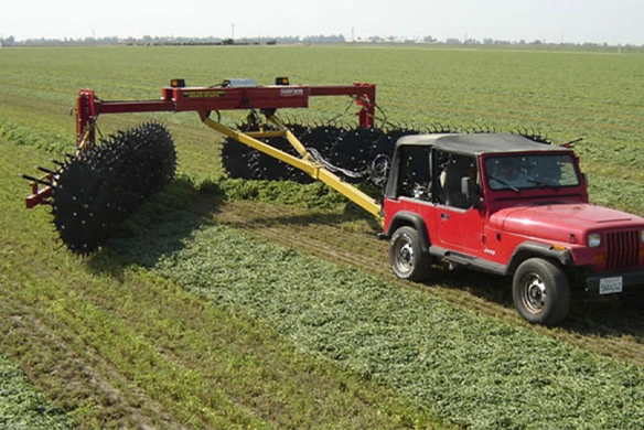 Side view of DARF 1017 rake in action in the field with wide raking arms