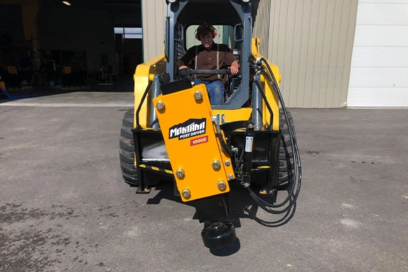 Montana Post Driver 1000E mounted on a skid steer, prepared for driving posts on a job site.