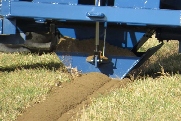 Close-up of OTECO track filler depositing soil into a field groove