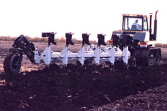 Wilcox HD pull-type plow operating behind tractor in field, performing deep tillage with high-efficiency moldboards for improved soil preparation.
