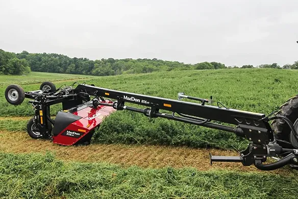 MacDon R1 Series pull-type mower cutting thick forage under a gray sky.