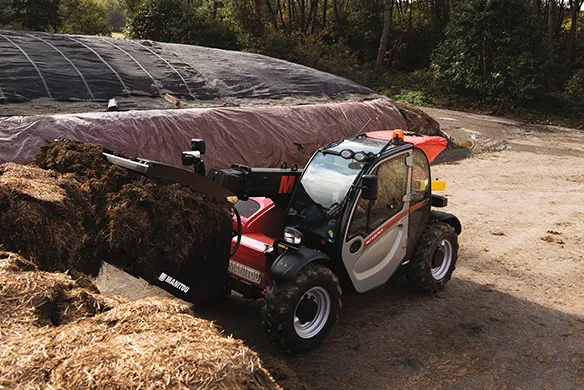 Manitou agricultural telehandler loading silage with a grapple attachment for efficient farm material handling