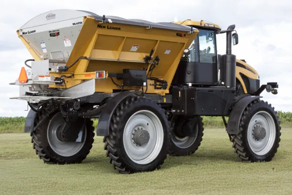 Rear quarter view of yellow New Leader manufacturing ag spreader.