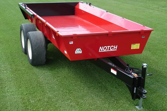 Red Notch manufacturing hydraulic dump wagon on display on a green grass field.