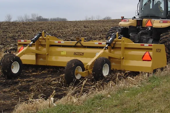 Notch Manufacturing land leveler working in a corn field on a gray, cloudy day.