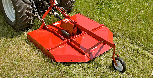 Farm King rotary cutter being pulled by a tractor in a field