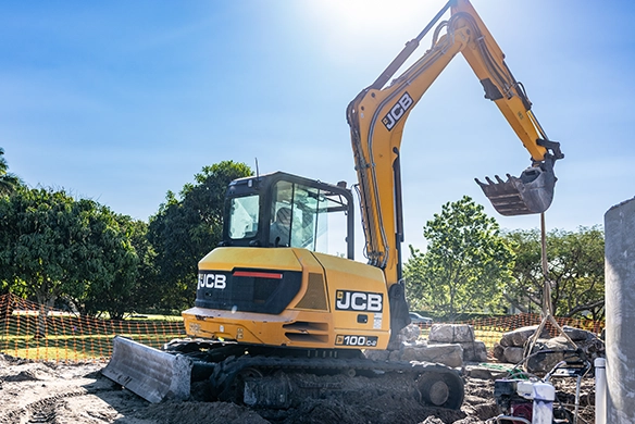 JCB 100Z-1 mini excavator lifting heavy material using a bucket and lifting chain on site