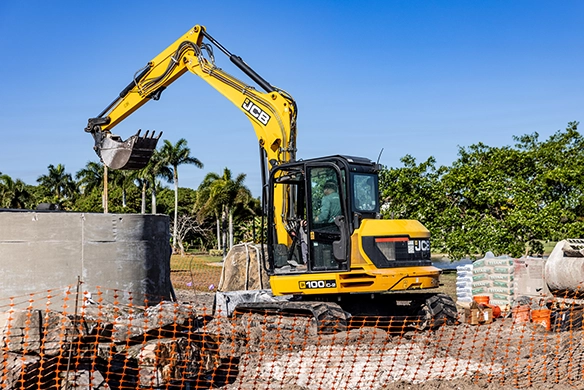 JCB 100Z-1 mini excavator working behind safety fencing on a residential construction project