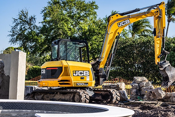 JCB 100Z-1 mini excavator excavating and positioning material near a concrete structure