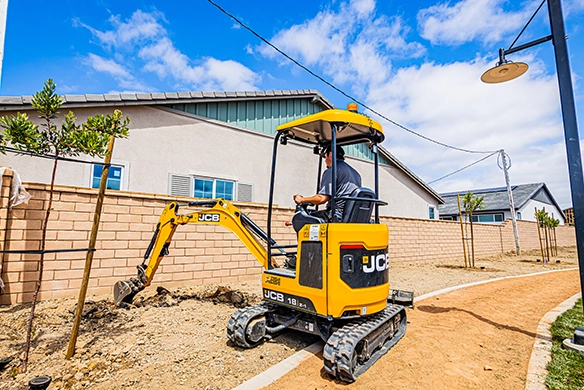 JCB 18Z-1 mini excavator trenching along a residential pathway during landscaping work