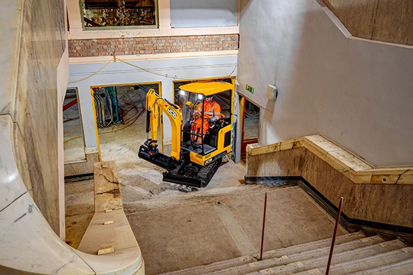 JCB 19C-1E electric mini excavator working inside a construction site with tight access and stairways