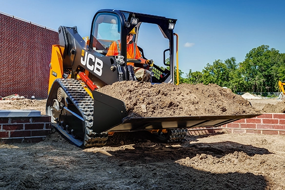 JCB 215T compact track loader carrying soil with front bucket on a construction site