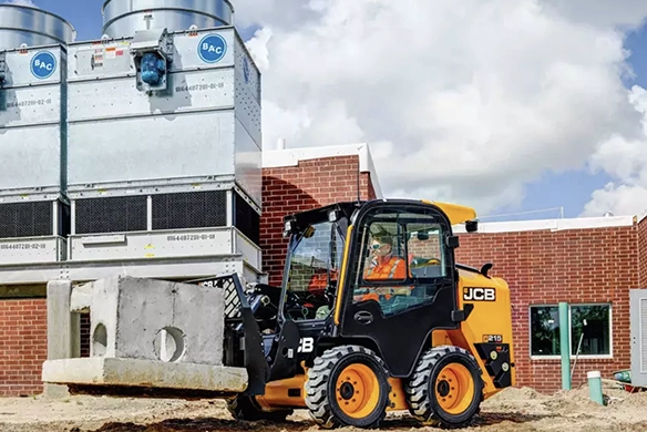 JCB 215 skid steer loader positioning a concrete block at a commercial construction site