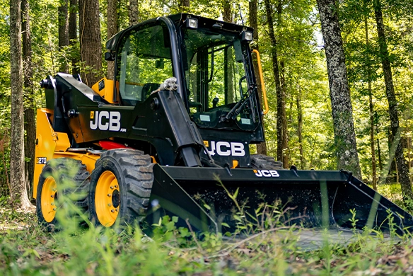 JCB 270 skid steer loader working with front bucket in a woodland environment