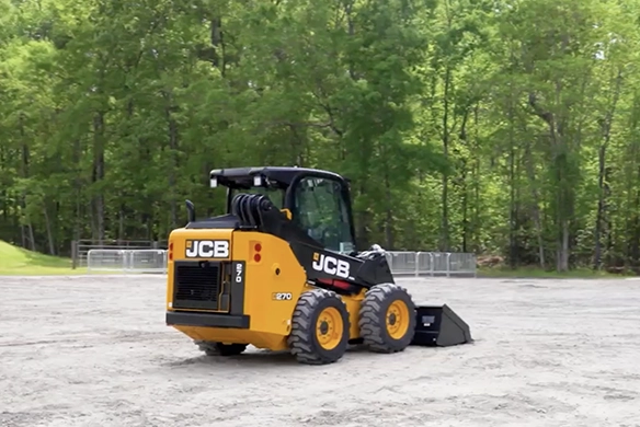 Rear view of JCB 270 skid steer loader maneuvering across a prepared work area