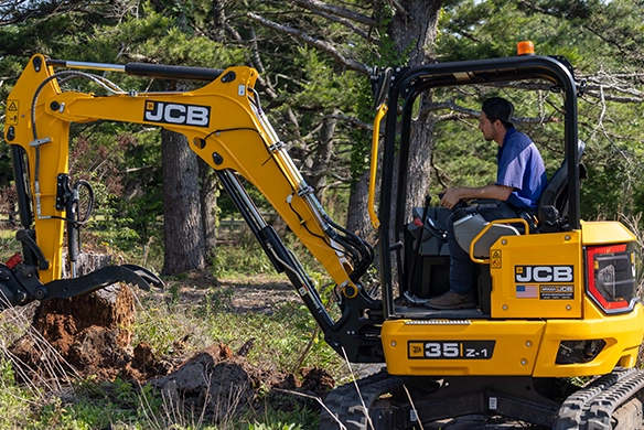 Side view of JCB 35Z-1 mini excavator trenching near trees with compact zero tail swing design