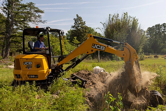 JCB 35Z-1 mini excavator excavating soil in a rural outdoor environment