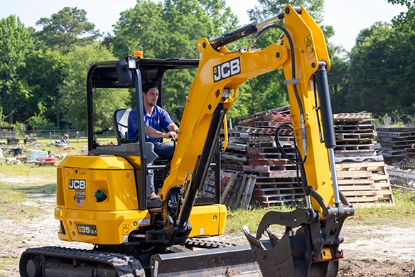 JCB 35Z-1 mini excavator working on a construction site with stacked building materials in the background