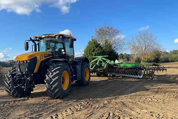 JCB 4000 Series agricultural tractor pulling a tillage implement in a field, showcasing high-horsepower performance and soil preparation capability