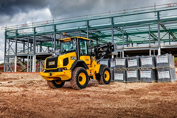 JCB 411 wheel loader on construction site with steel frame building structure under construction in the background