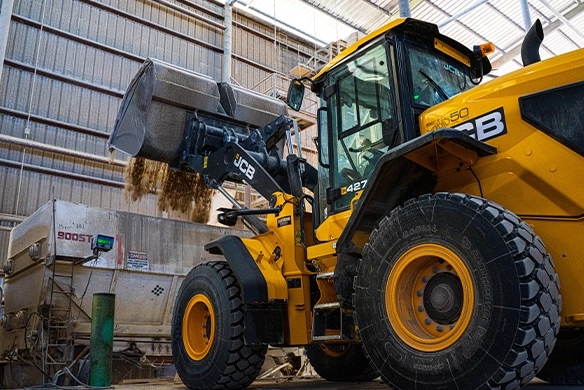 JCB 427 Agri wheel loader loading bulk agricultural material at a processing facility