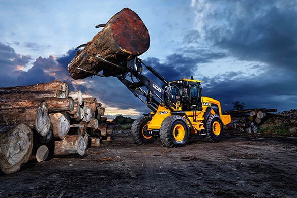 JCB 427 Agri wheel loader handling large timber logs in an outdoor environment