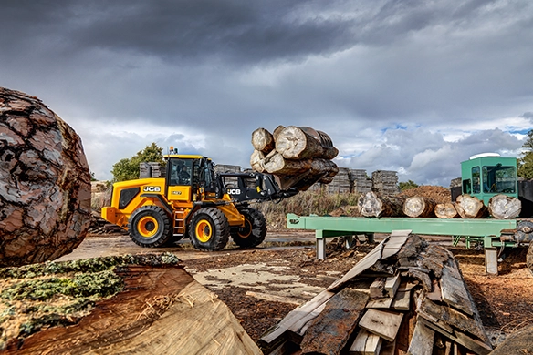 JCB 427 Agri wheel loader handling large timber logs in an outdoor environment