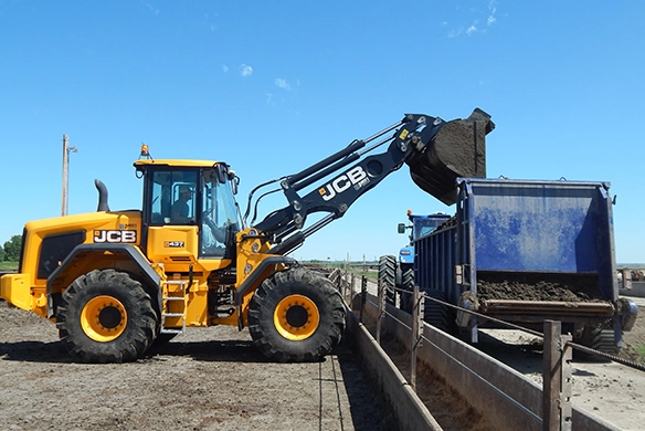 JCB 437 wheel loader loading material into a trailer using front bucket