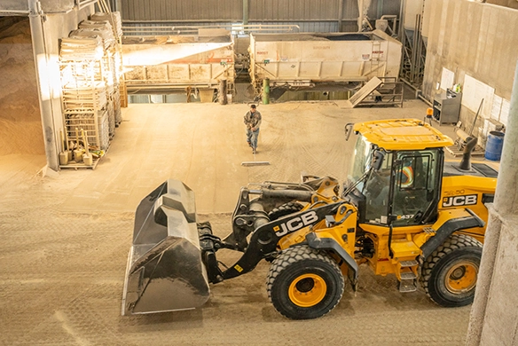 JCB 437 wheel loader operating indoors with large bucket in a handling facility
