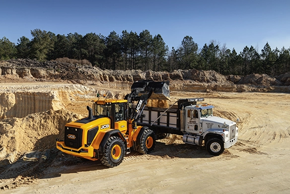 JCB 437 wheel loader loading a truck at a job site