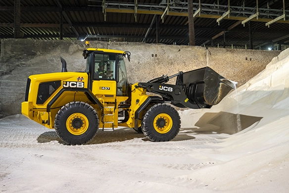 JCB 437 wheel loader working with material inside a covered storage shed